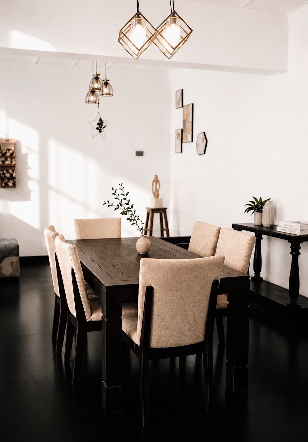 NDB dark wood dining table with six cream upholstered chairs under caged pendant lights.